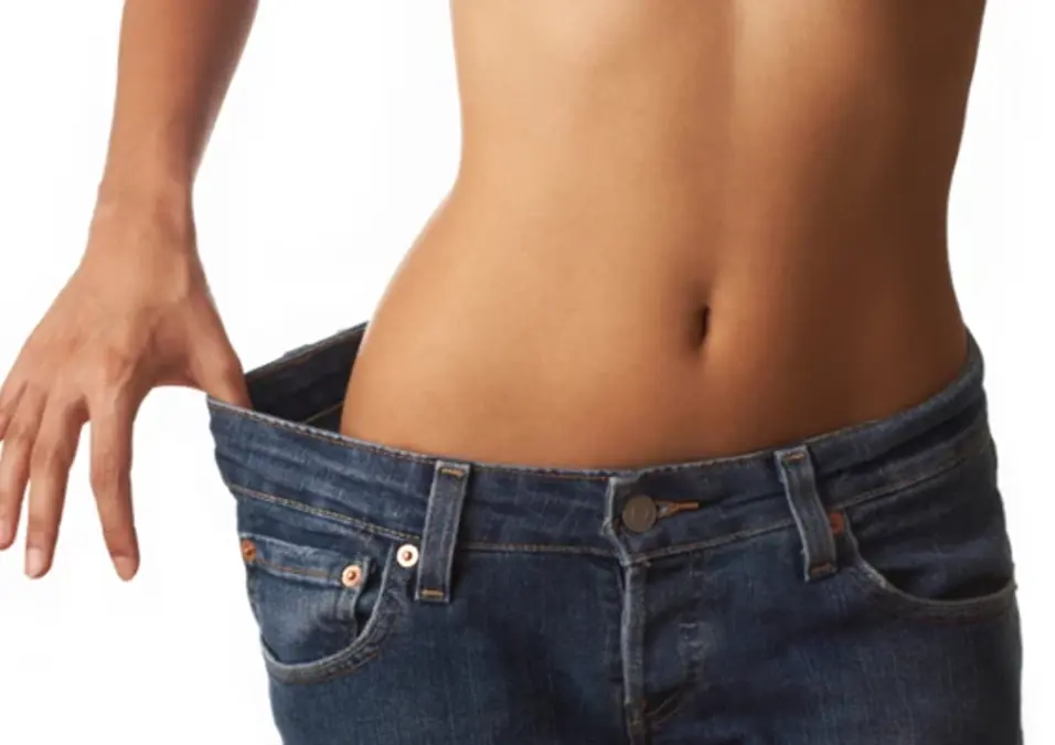 Fit waist in loose jeans, showing weight loss and slim stomach