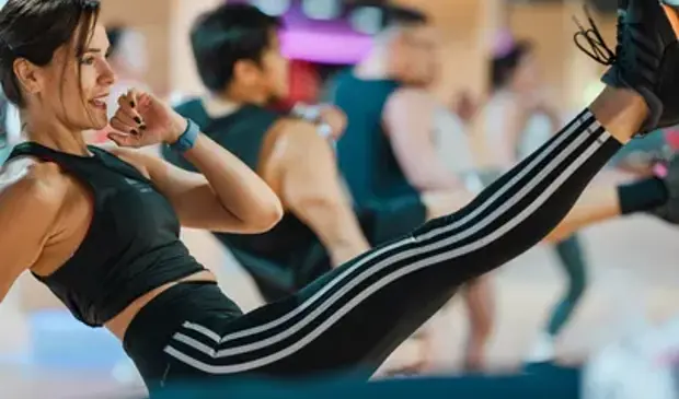 Female BODYCOMBAT participant performing a high kick during a group fitness class at GymNation.