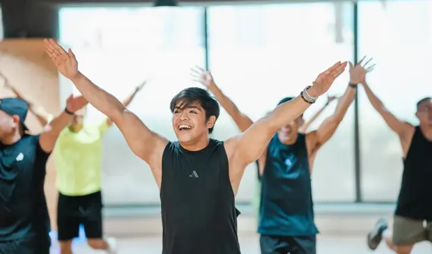 GymNation members smiling and raising their arms during a fun and energetic BODYBALANCE group class